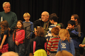 Peter Yarrow plays guitar with audience members around him.