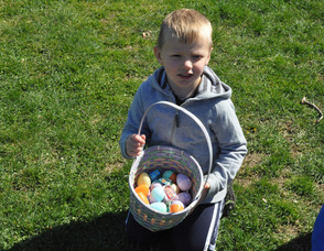 Max Faye, age 4, shows off his basket of eggs in Newton.