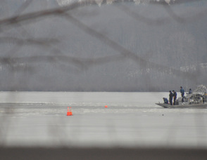 An officer (far left) on the boat lays down a buoy to mark a location.