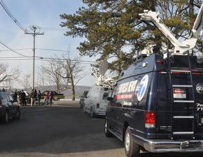 News vans wait near the lake.