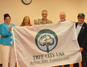 Mayor Helen Le Frois and members of the Shade Tree Commission hold up the Tree City USA flag, that will fly in various locations throughout town.