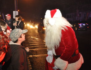 Santa hands out candy canes to children in front of the municipal building.