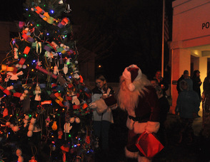Santa inspects the ornaments on the tree.