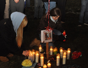 Two friends of the victims place items at the memorial this evening.