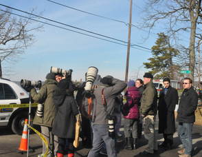 Members of the media wait behind the police tape.