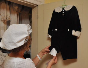 Allyn Perry inspects one of the outfits worn by the Cooper children in the early 20th Century.