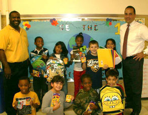 Jason Robinson of 8 to 8, left, stands with Ed Acevedo, Principal of Hazel Elementary, and students as they receive their school supplies