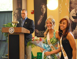 Thomas S. Russo, Jr. at the podium, as Miss Newton 2012, Ashley Iliff, and Miss Newton 2011 Kayla Sibblies, smile at the sidelines.