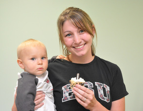 Marisa Hollenback with son Asher, 10 months, hold up a Cookies and Cream cupcake.