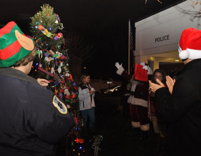 Santa holds up his hands in excitement as the tree is illuminated.