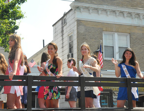 A bevy of beauty queens waves from atop one of the military vehicles.