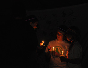 Team members speak in the glow of their candles.