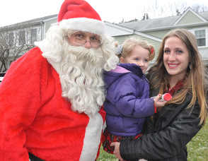 Santa greets Jillian Ackerman, age 3, with her mom, and gives her some candy.