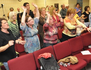 Members of the crowd raising their hands during praise and worship.