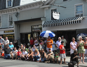 Locals sit and wave flags while watching the parade.