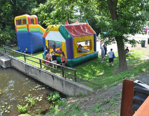 Children bounce in the bounce houses adjacent to the river..