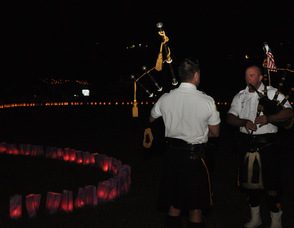 A pair of bagpipers play amongst the luminarias.