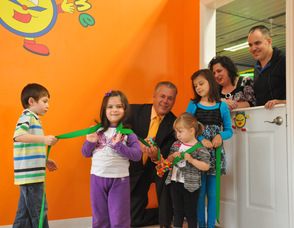 Mayor Michael Lensak at the ribbon cutting for Chuckle Time, with children Ryan Hudock, age 6, of Newton; Brianna Kash, age 3, of Byram, Samantha Hudock, age 3, of Newton; and Gabrielle Derewsky, age 7, of South Plainfield, N.J. Dawn and George Hudock, owners, overlook the ribbon cutting from the window.