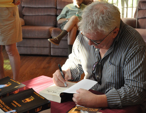 Max Zimmer signs a book at the book signing event held in his honor.