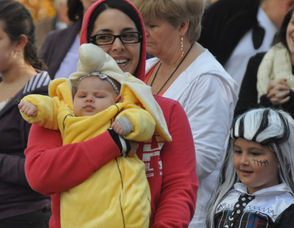 A baby banana being carried through the costume contest judging area.