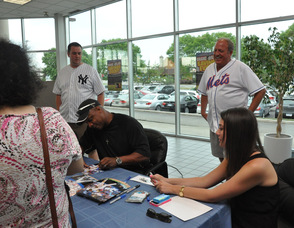 Bill Snouffer, General Sales Manager of Nielsen Dodge Chrysler Jeep Ram looks on as Strawberry signs autographs.