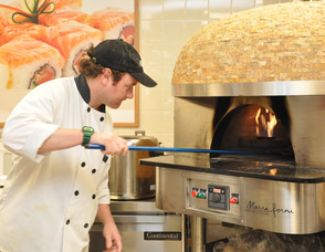 Billy Ganue places a pizza in the special Vesuvius Ash Brick oven, that can cook at temperatures of 900 degrees Fahrenheit.