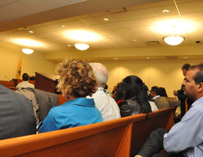 The crowd listens from within the adjacent conference room.