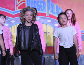 "Sandy" and "Danny" lead up the ensemble in "We Go Together".