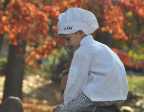 A young chef sits atop his Dad's shoulders.