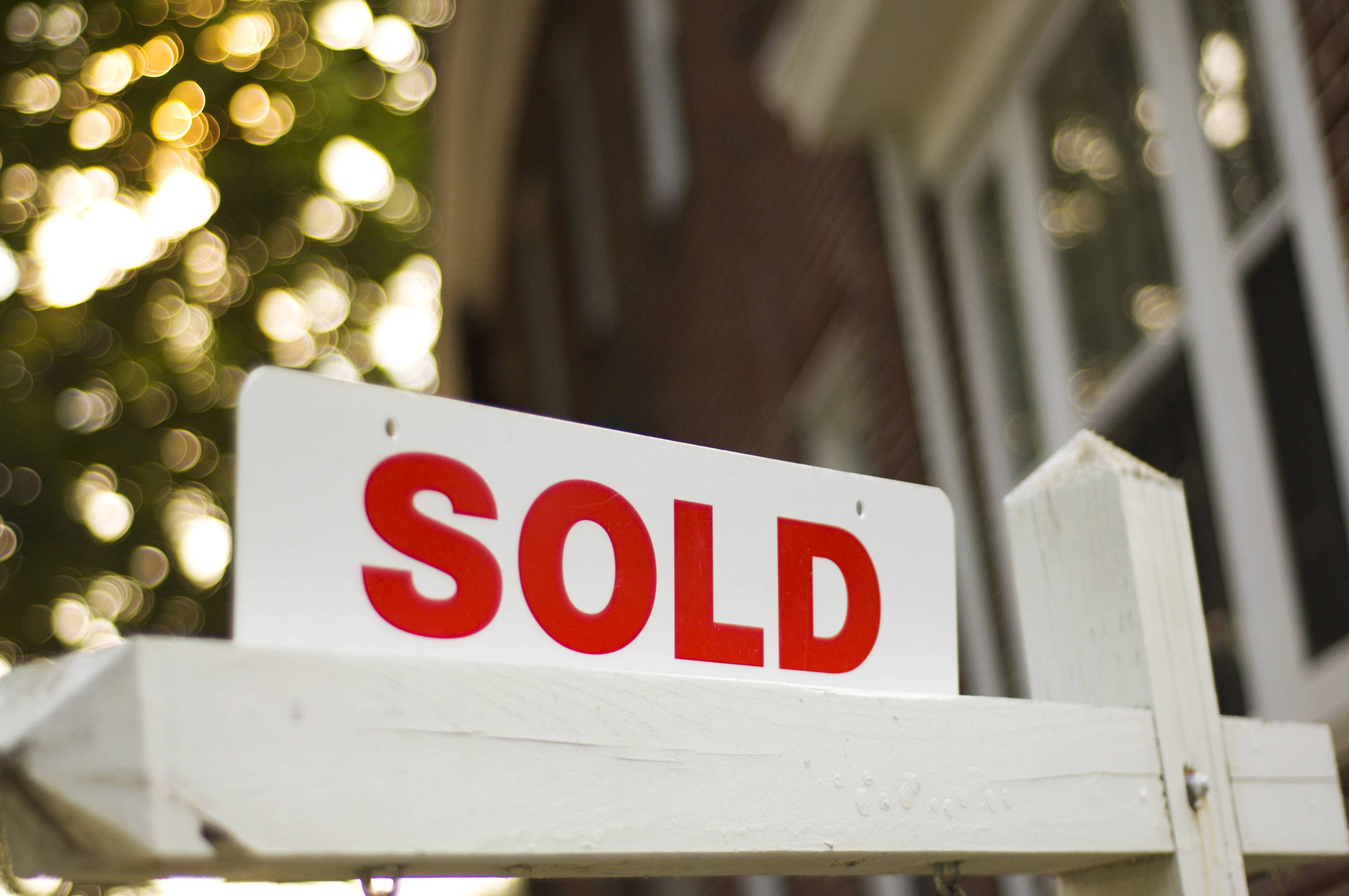 3b284df688644c458a55_Sold_Sign_Rider_close_up_w_blurry_house_tree_background.jpg