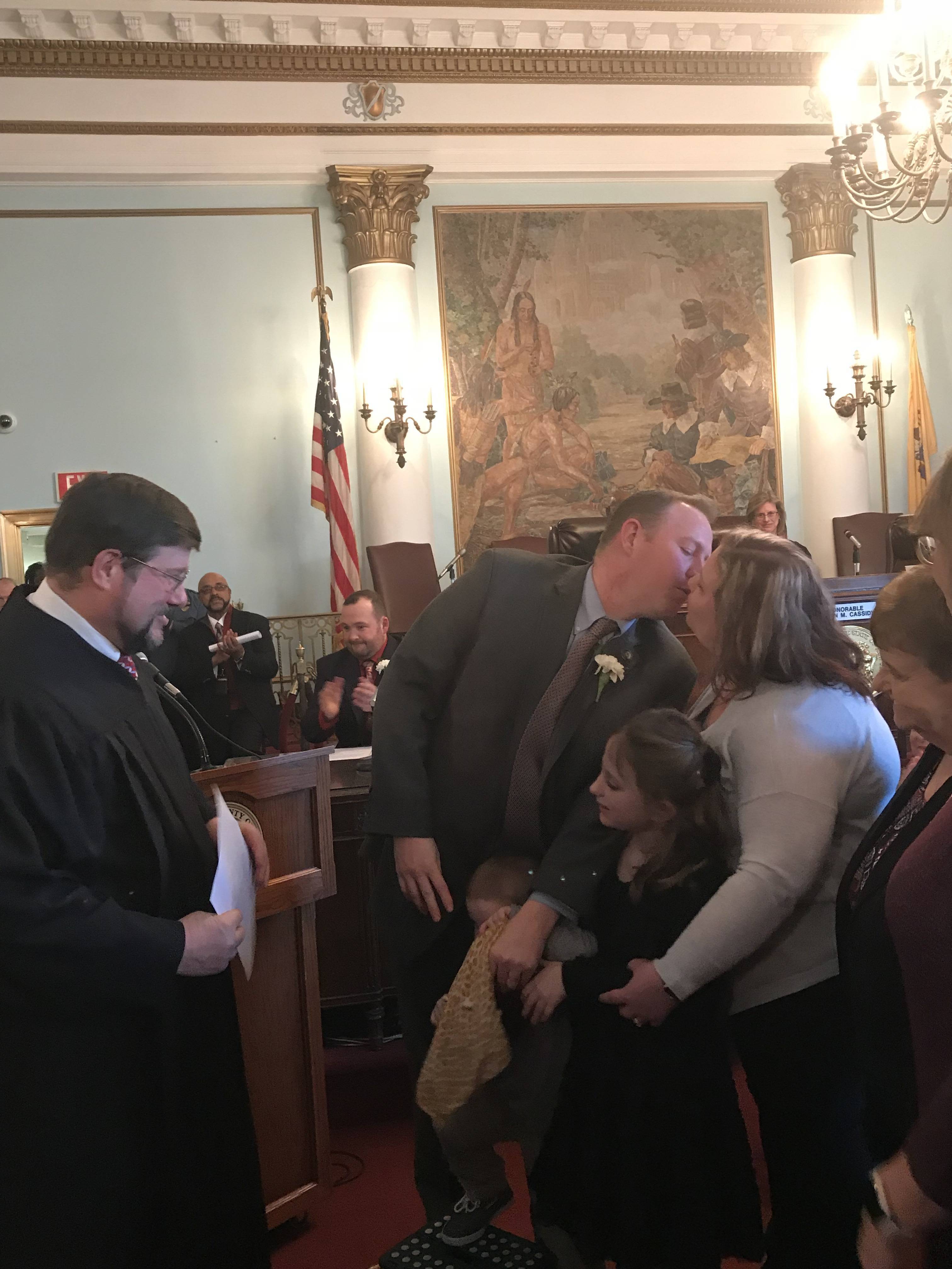 9af380d2d7dc7f90c322_d96be907da4961b35a03_Freeholder_Hudak_kisses_wife_after_being_sworn_in_by_his_Father.jpg
